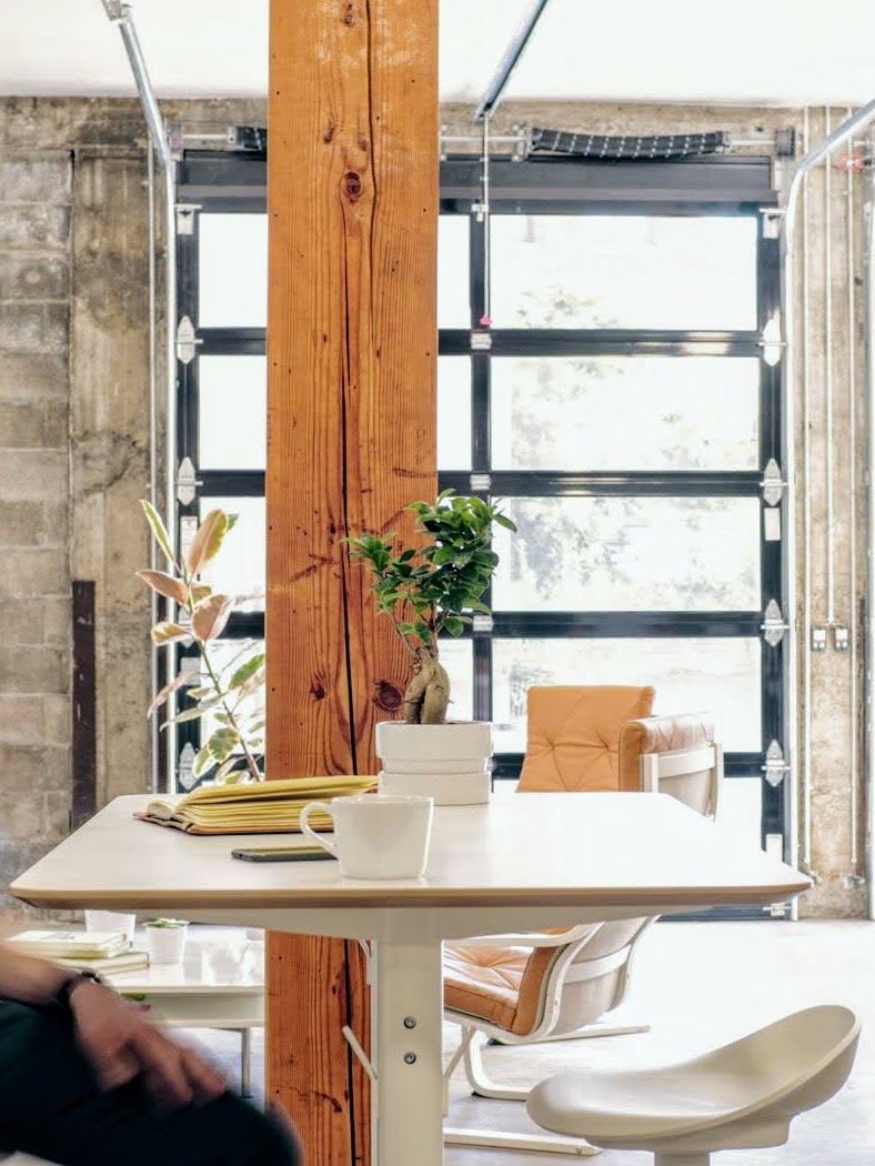 A team member walking through a bright studio with exposed brick, timber and natural light