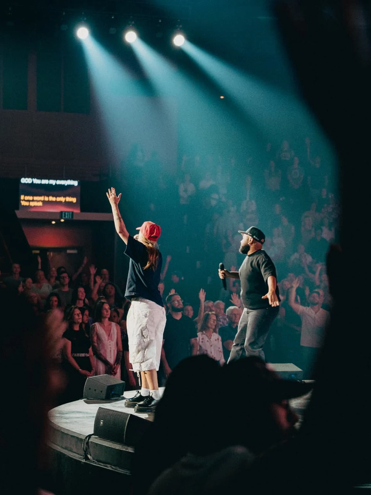 MISSION project image: a worship leader reaching toward a crowd under stage lights in a large gathering.
